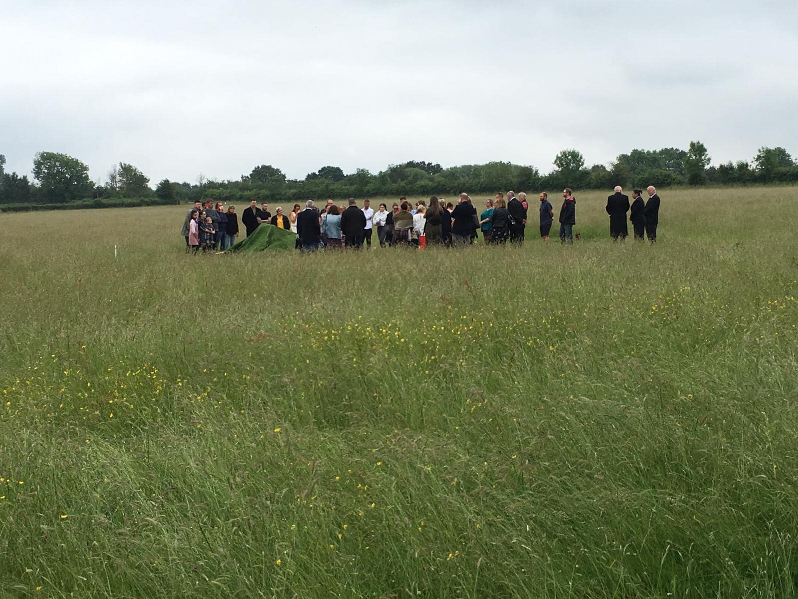 A small gathering for a funeral led by friends and family at Aylesbury Vale natural burial meadow.